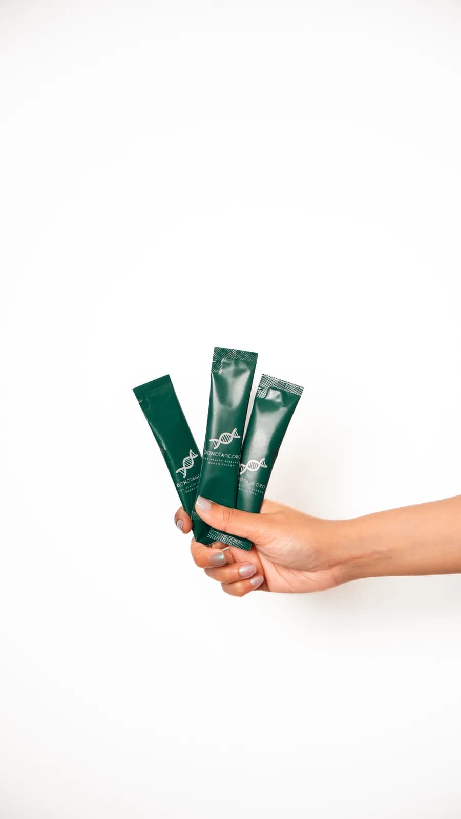 Three complete DoNotAge® Routine sachets held in a hand